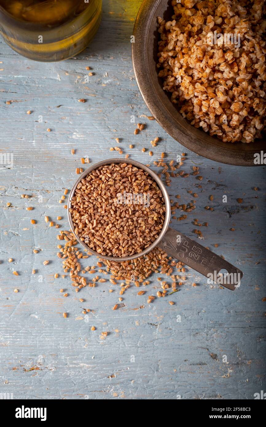 Bulgur Siyez in recipiente di misurazione in metallo su tavolo di legno blu. (Einkorn bulgur) Foto Stock