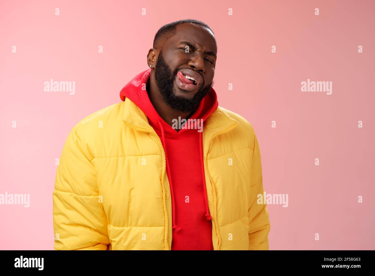 Uomo dal bearded africano, elegante e simpatico, con giacca gialla alla  moda felpa con cappuccio rossa mostra lingua sassy flirty sguardo  verricello fotocamera provare impressiona la donna finta Foto stock - Alamy