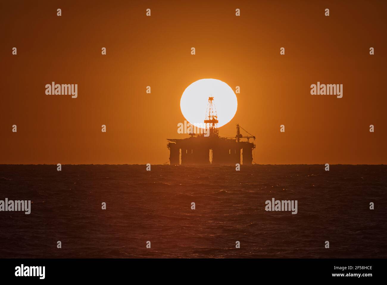 Tramonto su un carro di perforazione petrolifero sull'oceano Foto Stock