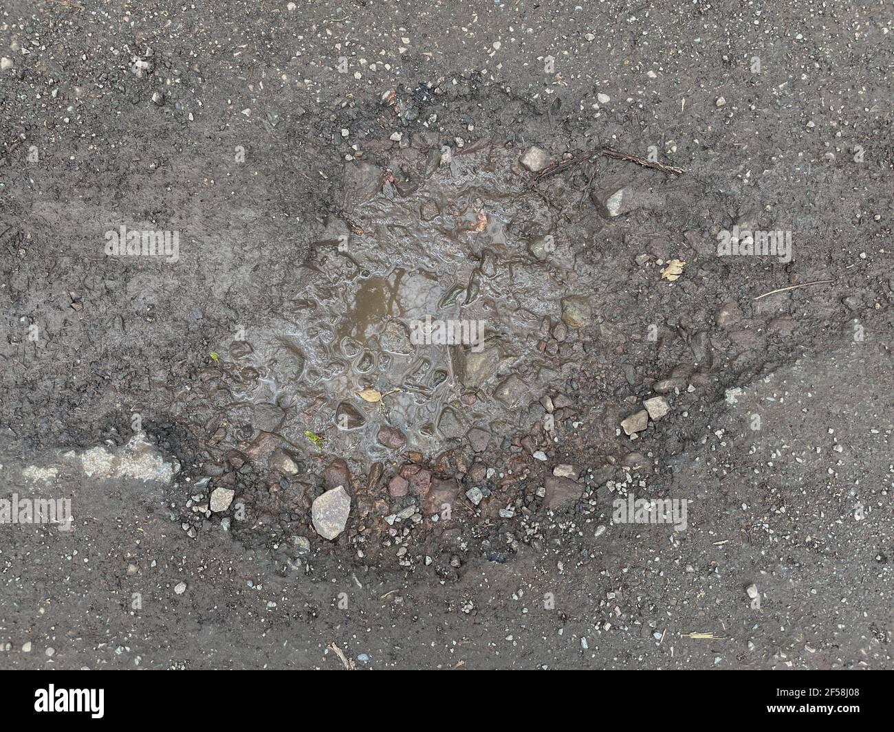 Primo piano su di un Pothole su una tranquilla strada di campagna Tarmac in Devon rurale, Inghilterra, Regno Unito Foto Stock