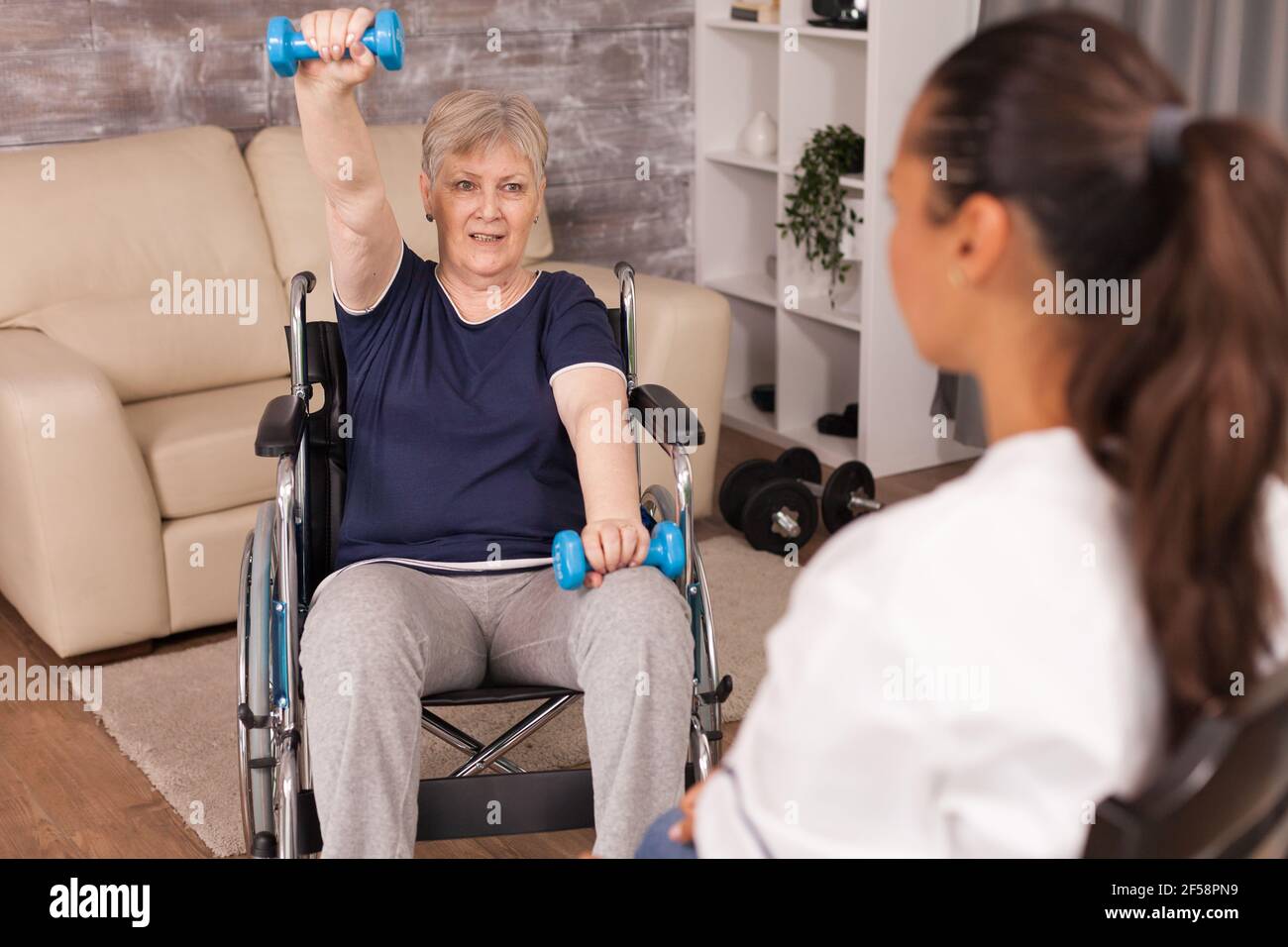 Donna anziana immobilizzata che fa esercizi alle spalle assistiti da infermiere. Disabile anziano ricoverato infermiera di aiuto professionale, cura di casa di riposo e riabilitazione Foto Stock