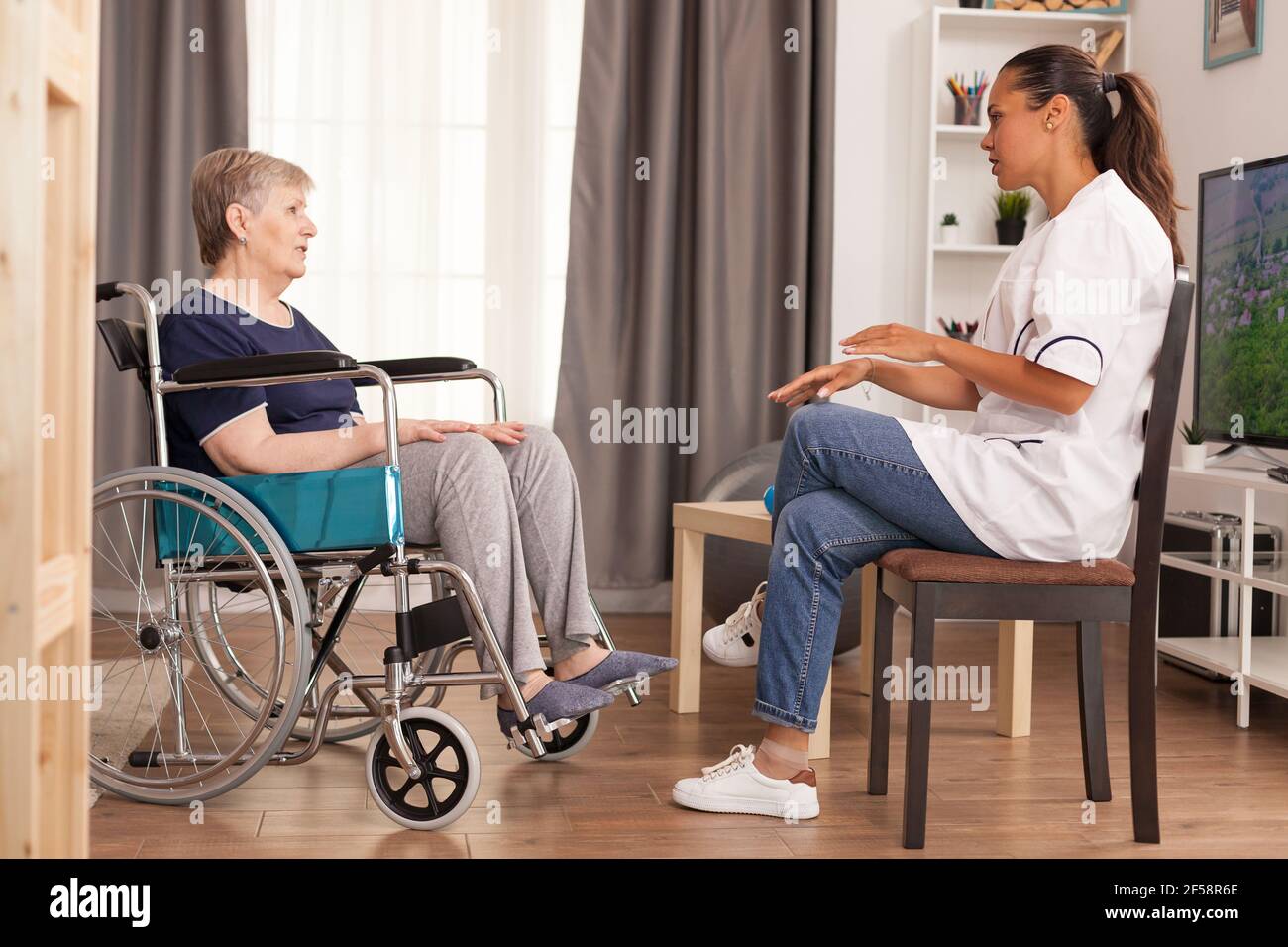 Controllo infermiere su anziana in pensione handicappata. Disabile anziano ricoverato infermiera di aiuto professionale, cura di casa di riposo e riabilitazione Foto Stock