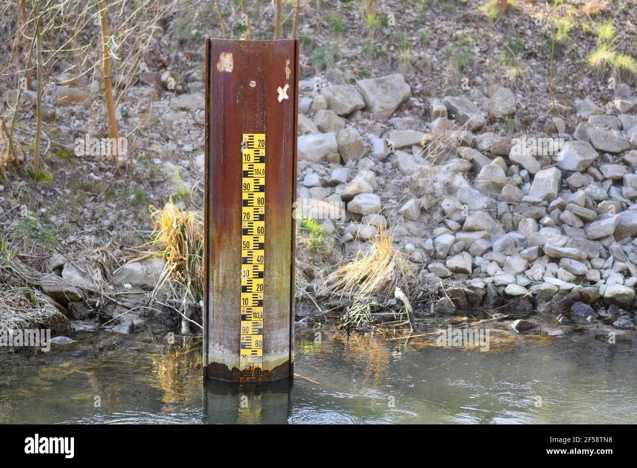 Indicatore di livello di allagamento metrico giallo nel fiume con acque basse livello Foto Stock