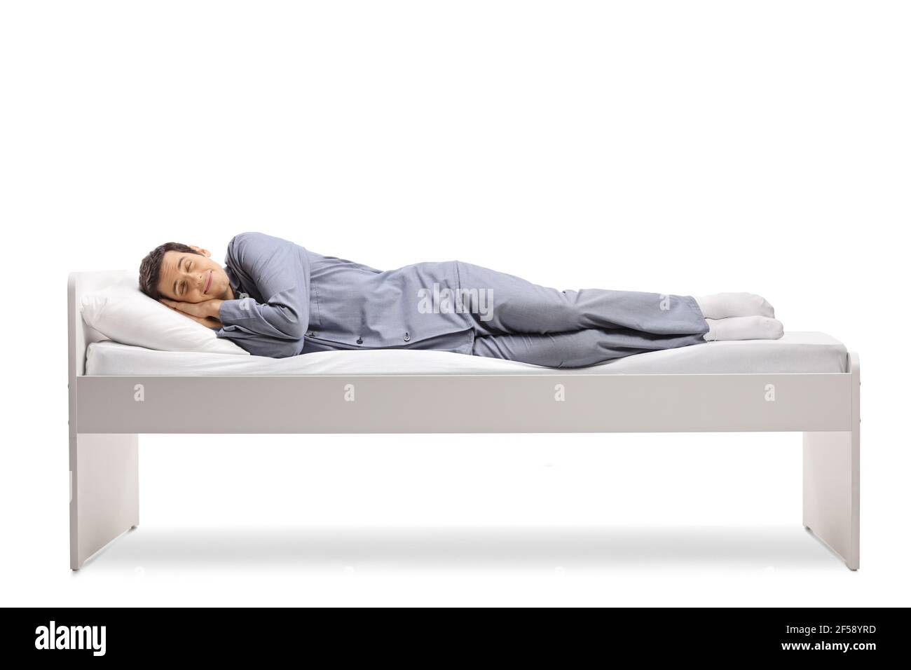 Un colpo di lunghezza pieno di un uomo che dorme pacificamente in un letto singolo isolato su sfondo bianco Foto Stock