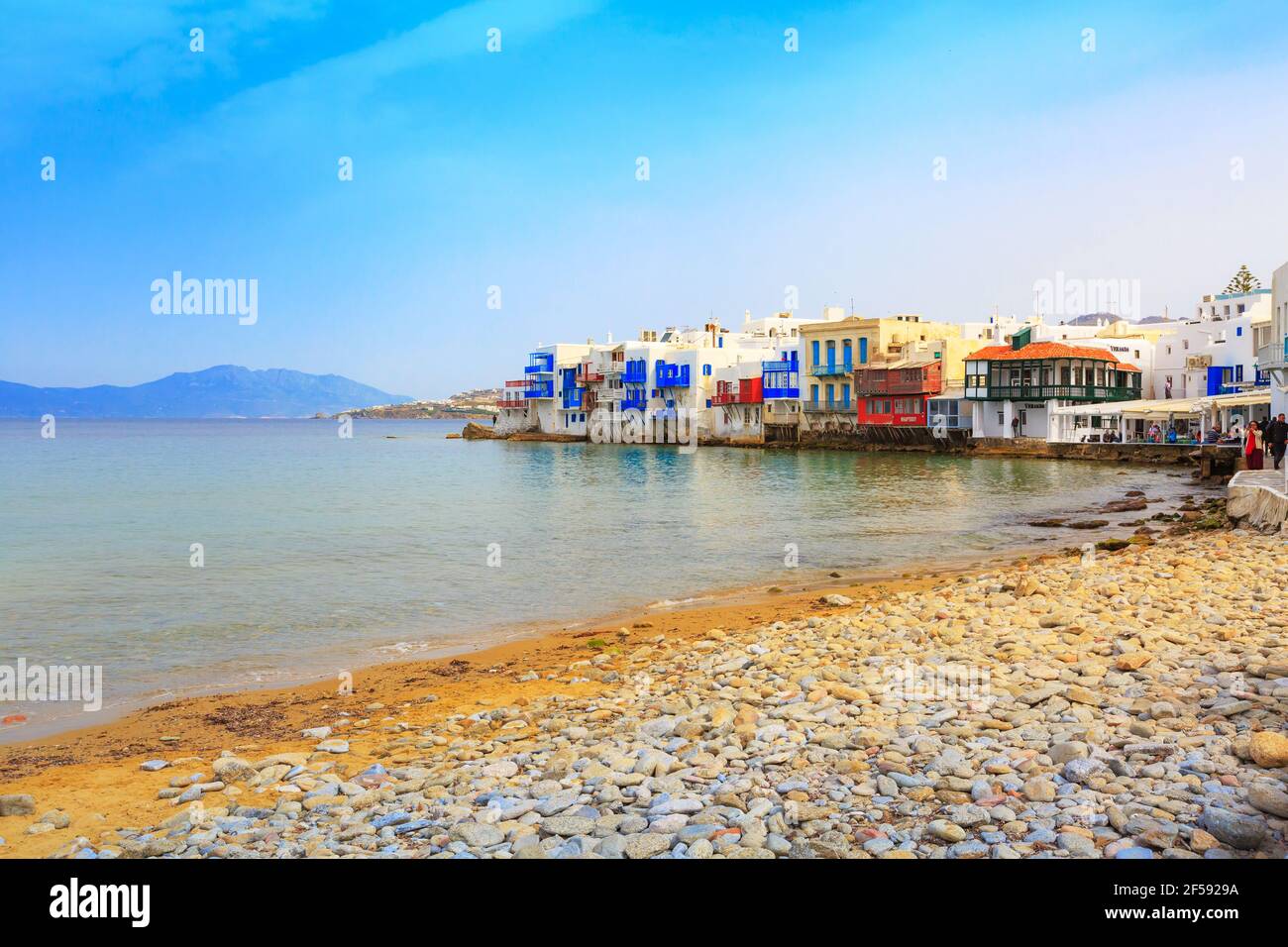 Mykonos, Grecia - 23 aprile 2019: Persone, passeggiata con sedie e tavoli in tipica taverna greca nella piccola Venezia parte della città di Mykonos Foto Stock