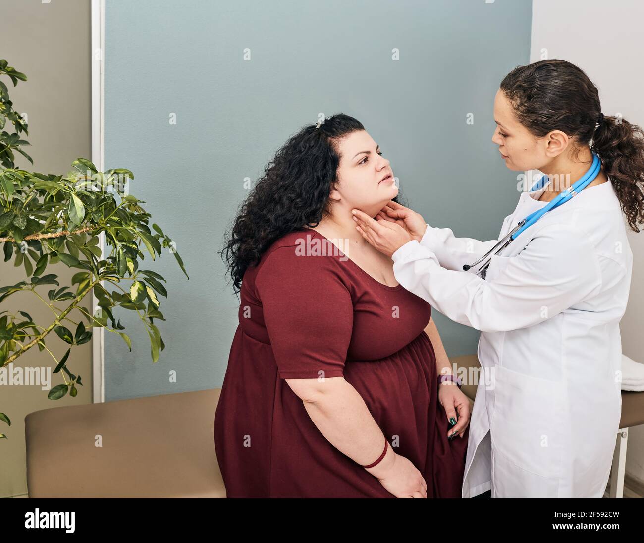 palpazione del medico del collo della donna grassa per la diagnostica di malattie della tiroide e ipotiroidismo. Foto Stock