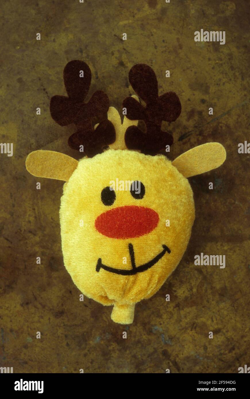Morbido giocattolo imbottito testa di renna di Natale con giallo pelliccia e naso rosso e sorriso amichevole Foto Stock
