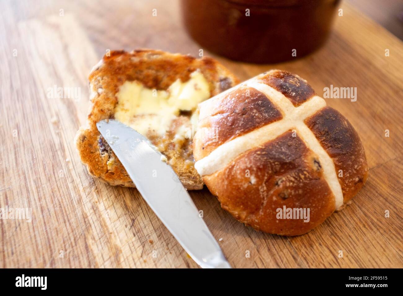 Tradizionale Hot Cross Bun con burro fuso un tradizionale per Pasqua UK - UNA croce calda è un dolce spicciato di solito fatto con frutta, segnato con una croce sulla parte superiore, e tradizionalmente mangiato il Venerdì Santo nel Regno Unito Foto Stock