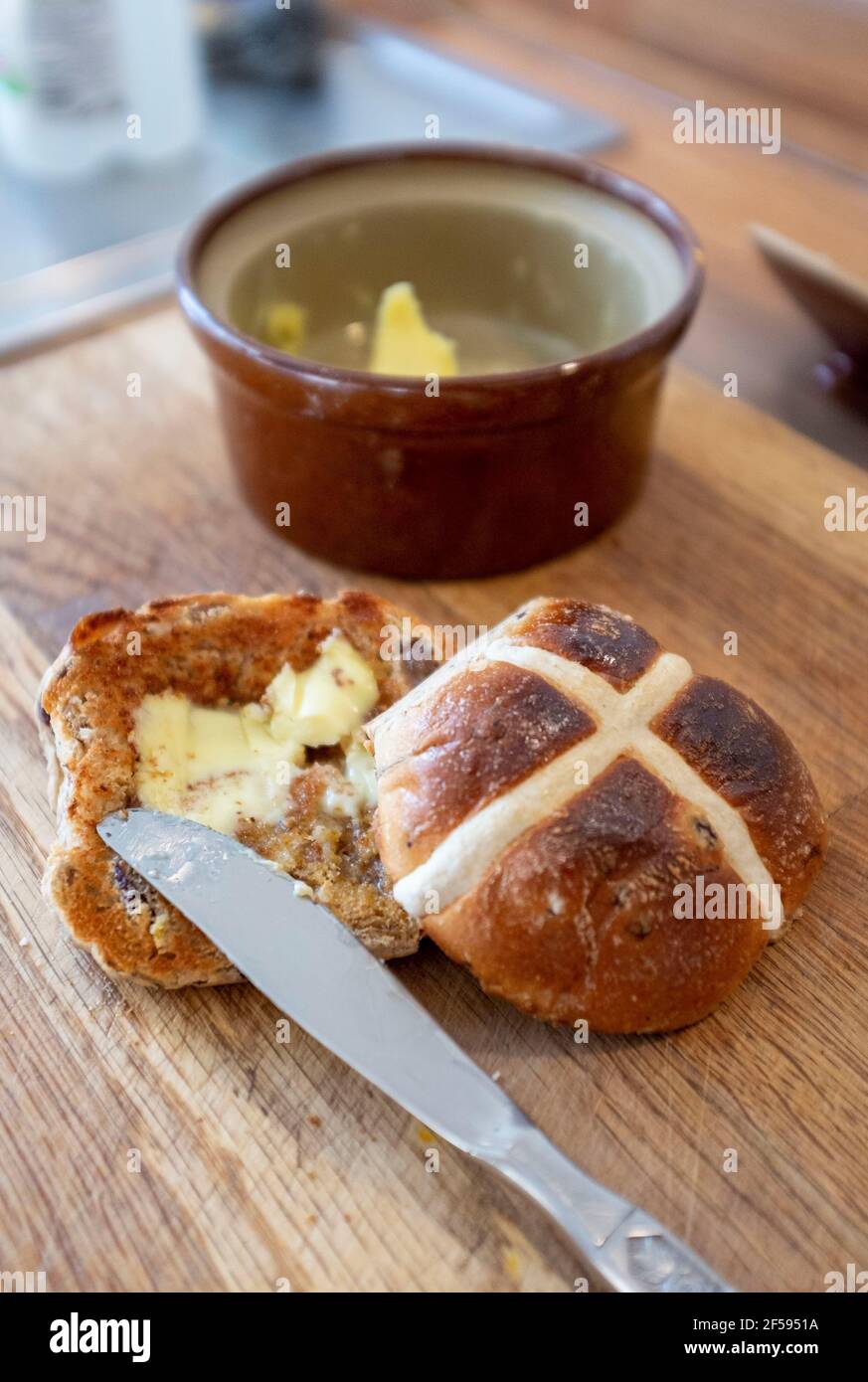 Tradizionale Hot Cross Bun con burro fuso un tradizionale per Pasqua UK - UNA croce calda è un dolce spicciato di solito fatto con frutta, segnato con una croce sulla parte superiore, e tradizionalmente mangiato il Venerdì Santo nel Regno Unito Foto Stock