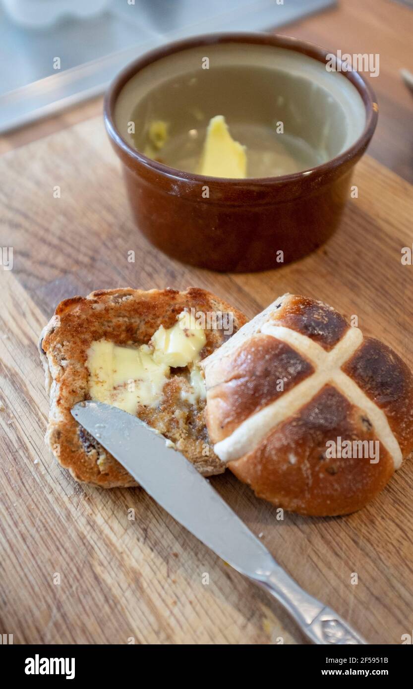 Tradizionale Hot Cross Bun con burro fuso un tradizionale per Pasqua UK - UNA croce calda è un dolce spicciato di solito fatto con frutta, segnato con una croce sulla parte superiore, e tradizionalmente mangiato il Venerdì Santo nel Regno Unito Foto Stock
