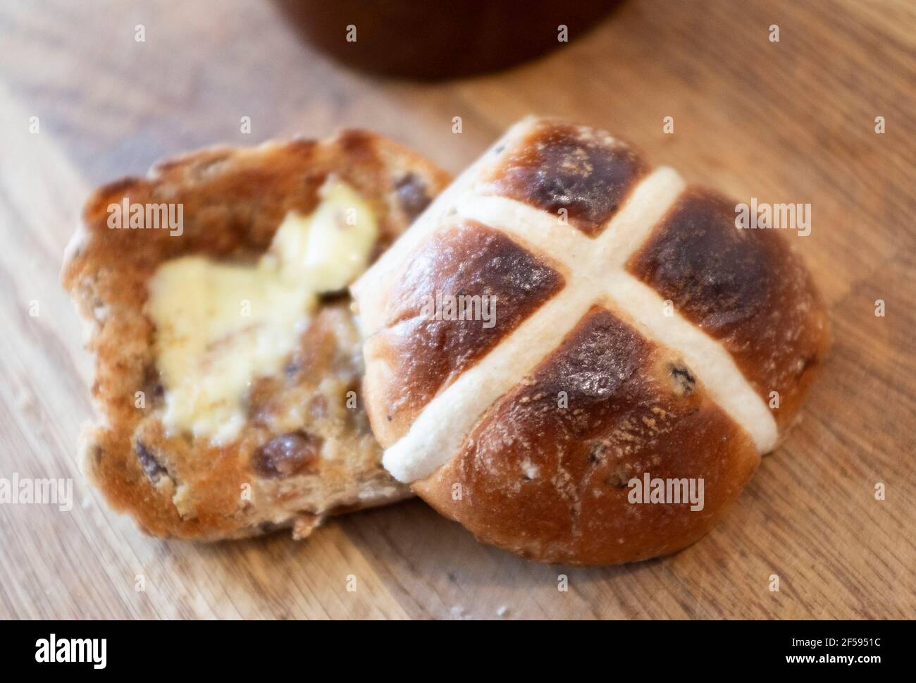 Tradizionale Hot Cross Bun con burro fuso un tradizionale per Pasqua UK - UNA croce calda è un dolce spicciato di solito fatto con frutta, segnato con una croce sulla parte superiore, e tradizionalmente mangiato il Venerdì Santo nel Regno Unito Foto Stock