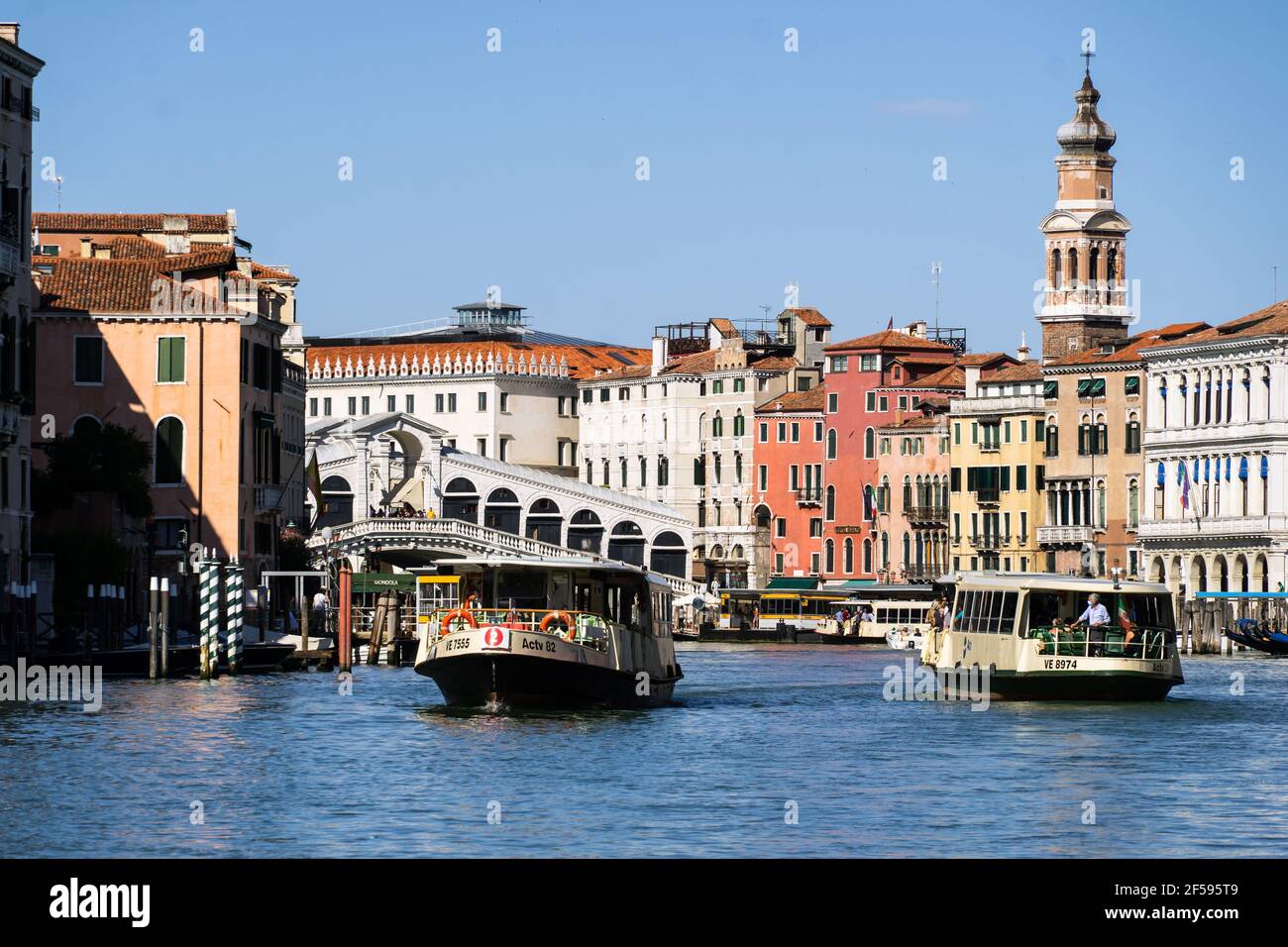 Venezia, Italia - Giugno 22 2020: Vaporetti che trasportano gente del posto e turisti navigano sul famoso Canal Grande di Venezia con il Ponte di Rialto nel bac Foto Stock