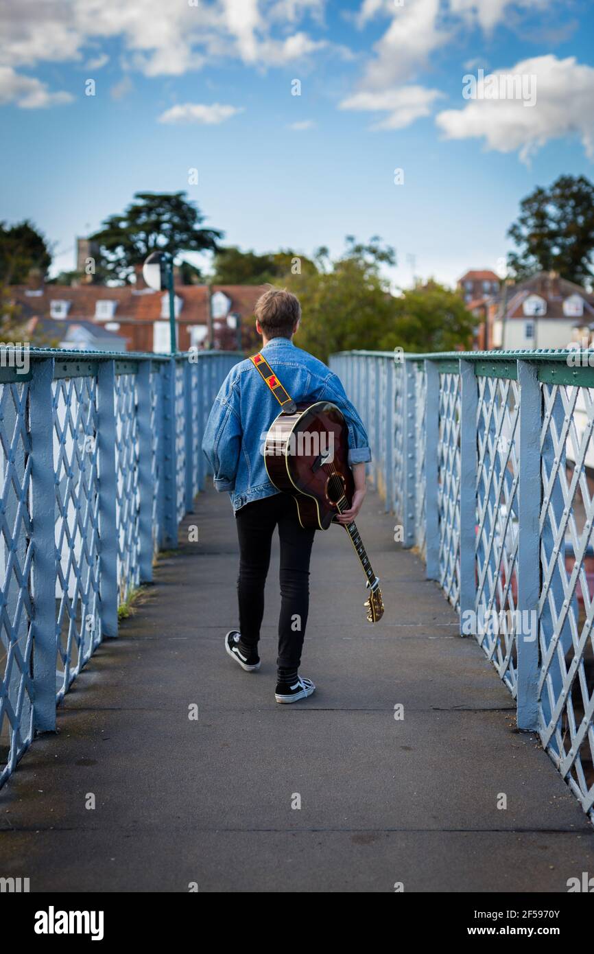 A 20 something female Waling Woodbridge, Suffolk, UK Settembre 13 2020: A 20 something female walking over a Raised bridge with sua chitarra acustica ha Foto Stock