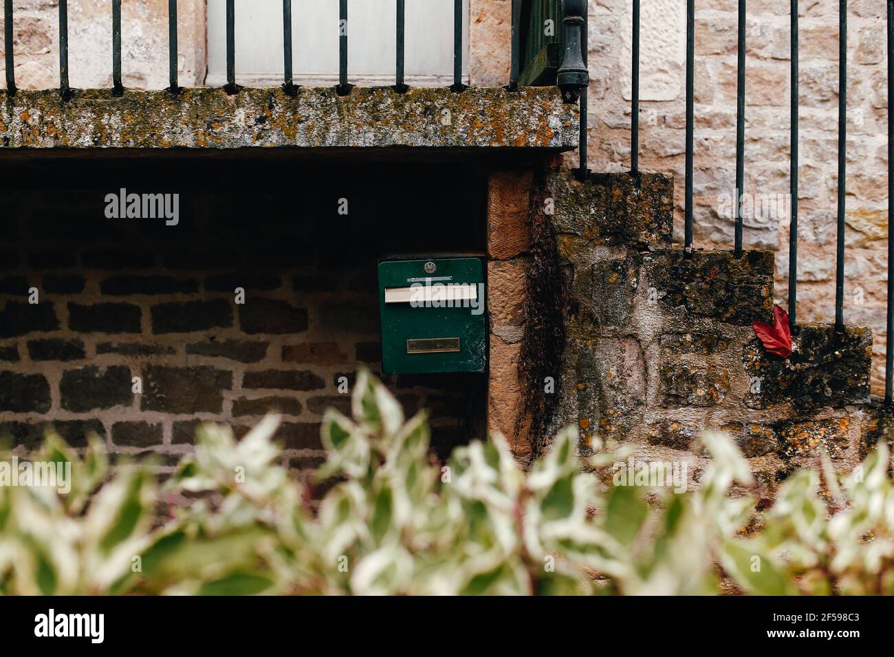 Scatola verde posta su muro di pietra sotto le scale. Foto di alta qualità Foto Stock