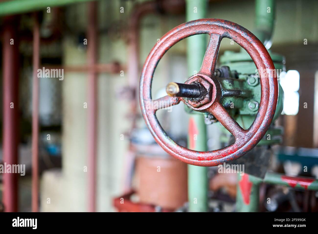 Valvola verde retrospettiva industriale chimica chiusura petrolchimica con selettiva mettere in primo piano il volante marrone montato con il collegamento della flangia attivato verde Foto Stock