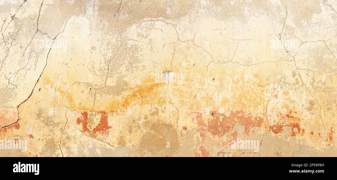 Una vecchia parete in cemento fessurato, dai toni caldi e ocra, dai toni pastello, da un ampio panorama Foto Stock