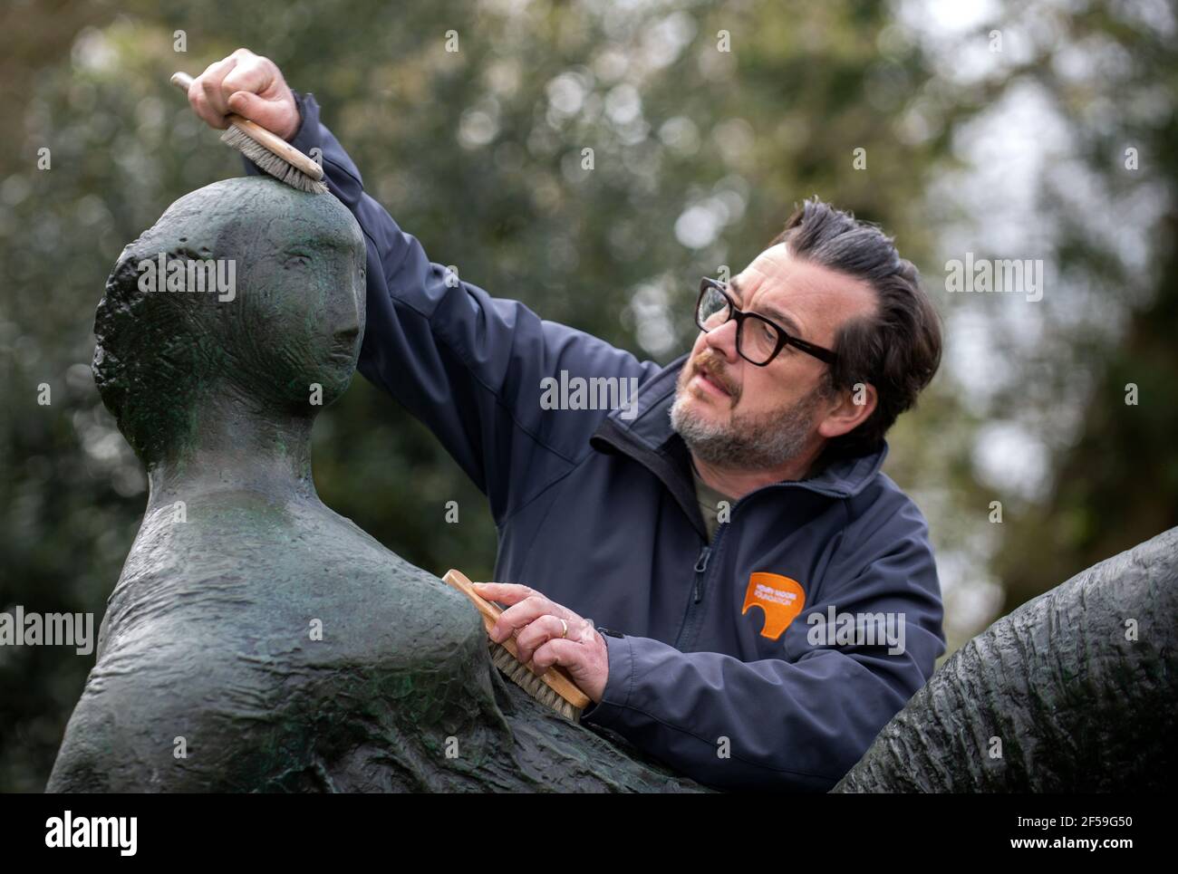 Il conservatore di sculture James Copper cere la scultura in bronzo 'Raped Reclining Figure' durante i preparativi per gli Henry Moore Studios e giardini a Much Hadham, Hertfordshire, per riaprire il 31 marzo dopo che le restrizioni di blocco sono attenuate. Data immagine: Giovedì 25 marzo 2021. Foto Stock