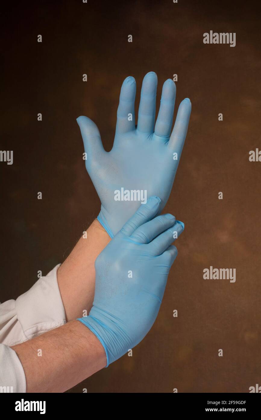 Uomo che indossa guanti blu chirurgici medici Foto Stock