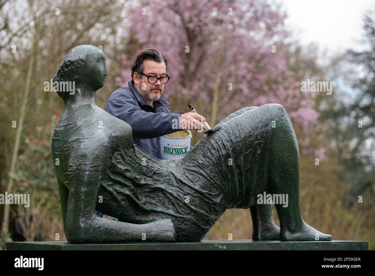 Il conservatore di sculture James Copper cere la scultura in bronzo 'Raped Reclining Figure' durante i preparativi per gli Henry Moore Studios e giardini a Much Hadham, Hertfordshire, per riaprire il 31 marzo dopo che le restrizioni di blocco sono attenuate. Data immagine: Giovedì 25 marzo 2021. Foto Stock