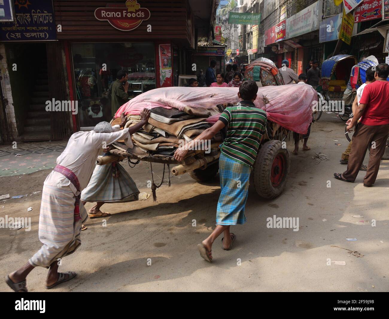I lavoratori di cuoio spingono i carrelli nel distretto di Hazaribagh, Dhaka, Bangladesh Foto Stock