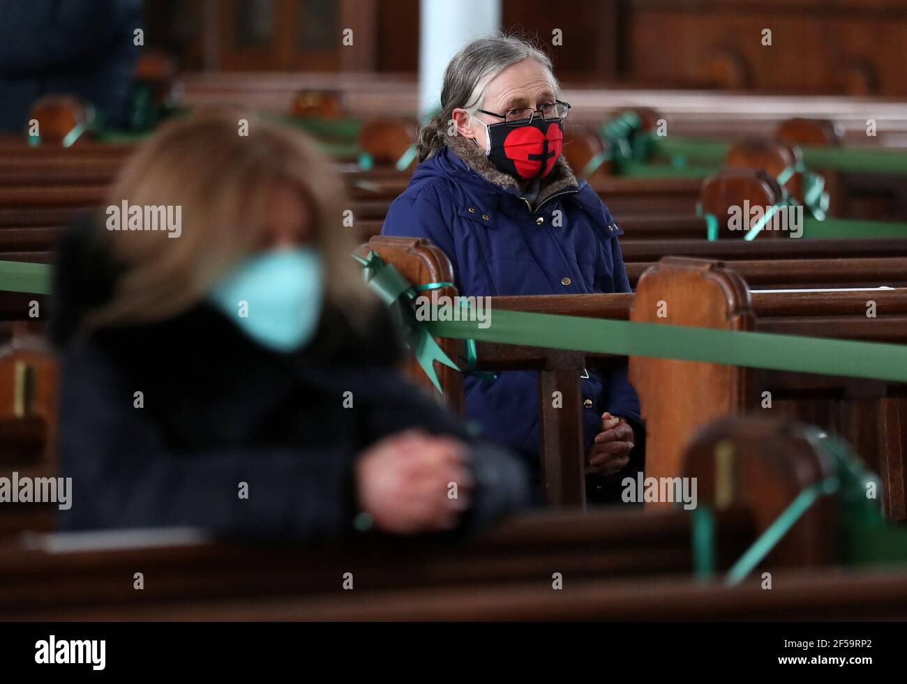 Un parishioner siede mentre il canonico Tom White tiene un servizio di massa al St Mary's Catholic Chuch a Calton, Glasgow, dopo che le norme del coronavirus che hanno forzato la chiusura delle chiese in Scozia e il culto pubblico criminalizzato sono stati considerati illegali dalla Corte di sessione. Le chiese saranno autorizzate ad aprire il venerdì sotto la guida del governo scozzese. Data immagine: Giovedì 25 marzo 2021. Foto Stock