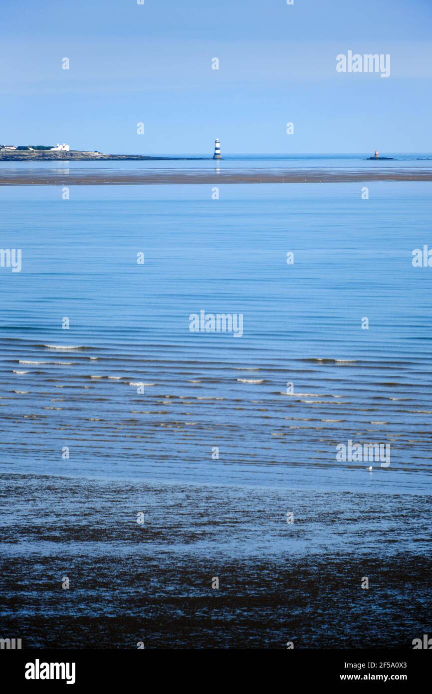 Una vista di un lontano Trwyn Du Lighthouse su Anglesey sopra il Lavan Sands a bassa marea, Llanfairfechan Foto Stock