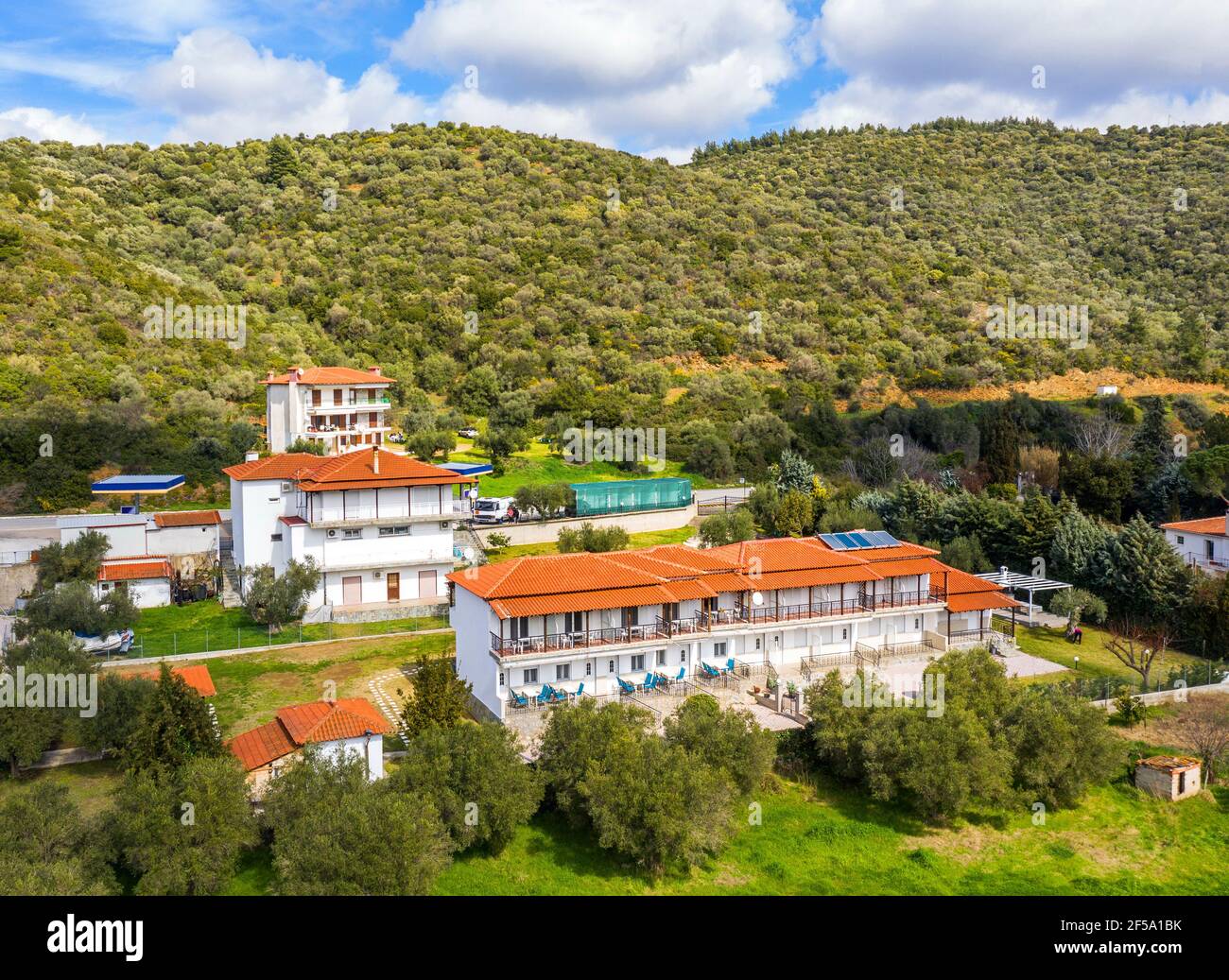 Vista dall'alto del drone aereo verso la Grecia campagna paesaggio estivo con case cittadine e case tetto in tegole rosse tra le verdi montagne della foresta, blu Foto Stock