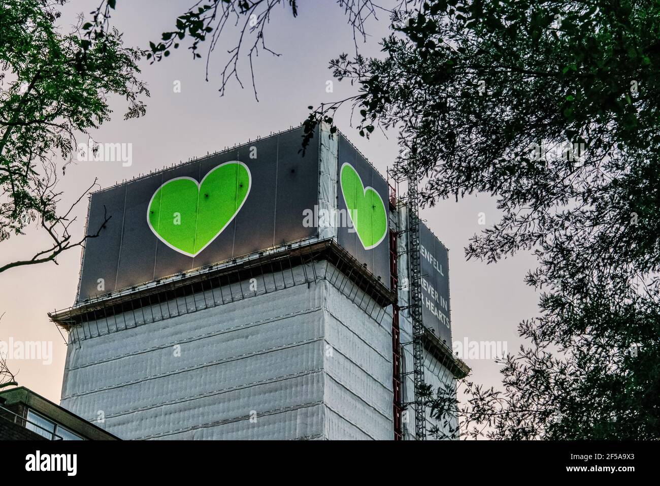 Grenfell Tower, un edificio affittato a West London, sorge sopra gli appartamenti sottostanti. Crepuscolo. Metà estate 2019. Motivo cuore verde. Foto Stock