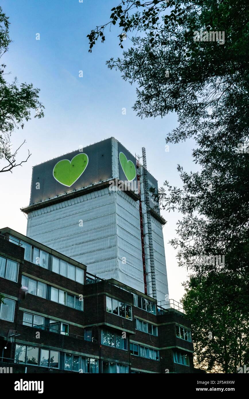 Grenfell Tower, un edificio affittato a West London, sorge sopra gli appartamenti sottostanti. Crepuscolo. Metà estate 2019. Motivo cuore verde. Foto Stock