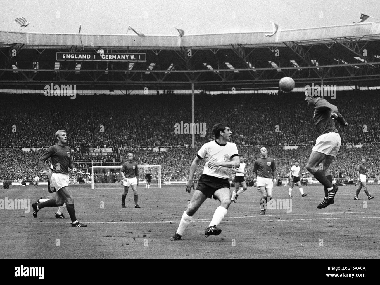 Inghilterra contro Germania occidentale finale della Coppa del mondo 1966, Wembley Stadium 20 minuti del primo tempo. Ray Wilson of England dirige la palla al Capitano Bobby Moore passando Lothar Emmerich della Germania Ovest Foto di Tony Henshaw Archive Foto Stock