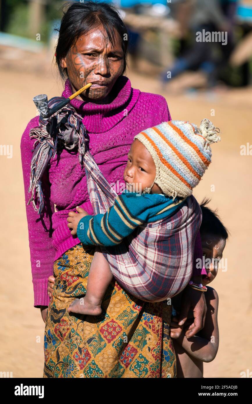 Donna con tatuaggio facciale tradizionale che trasporta il bambino, Mindat, Myanmar Foto Stock