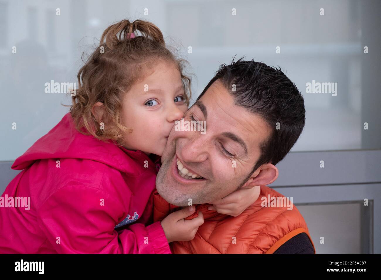 una bambina di 4 anni abbracciando la mano del padre e baciando Foto Stock
