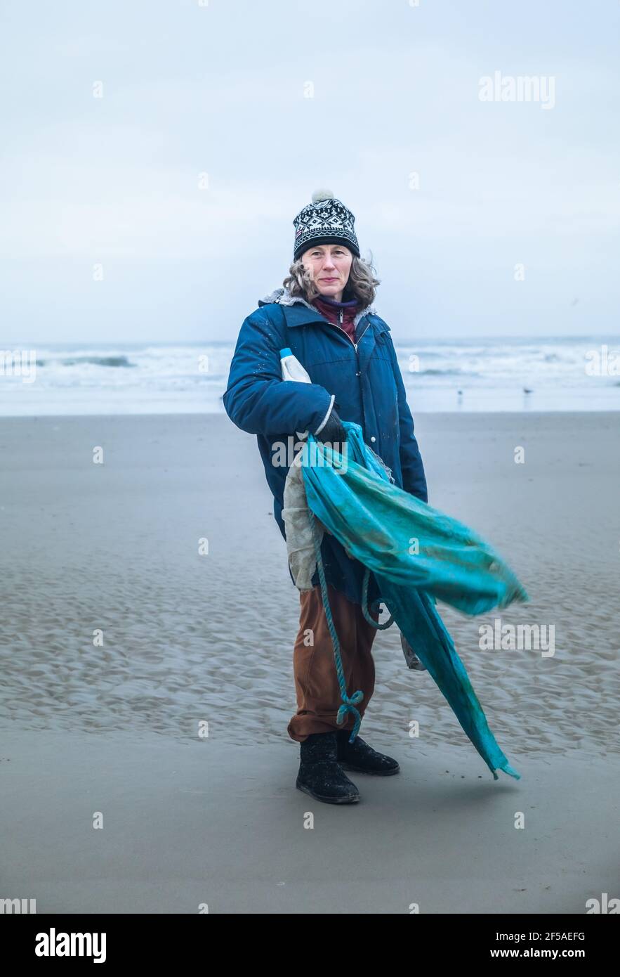 Donna matura nel suo 50 pulizia Up Beach su UN Giornata ventosa in Danimarca Foto Stock