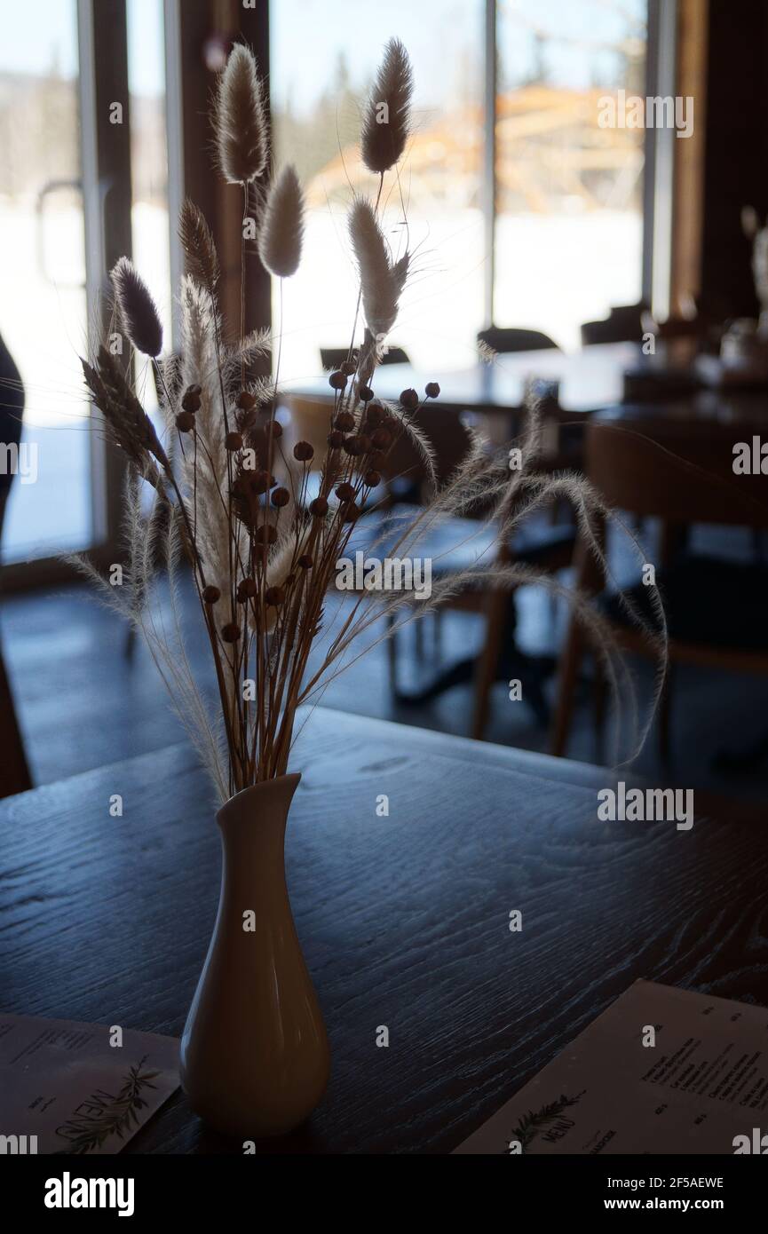 Un bouquet di fiori secchi si trova in un vaso sopra una tabella contro t Foto Stock