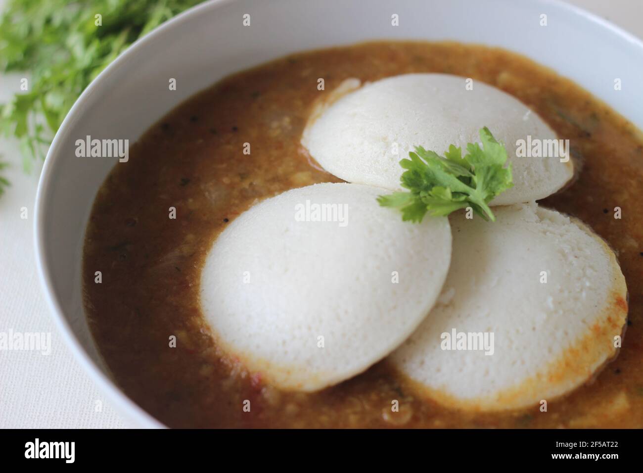 Idli Sambhar un cibo indiano tipicamente fatto in India del Sud ma gradito e preparato quasi in tutte le parti dell'India. Placcato bene. Scatto su sfondo bianco Foto Stock