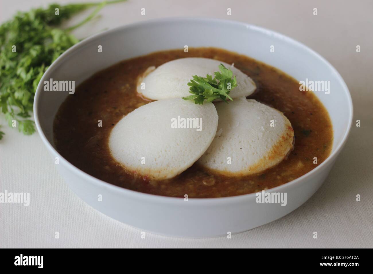 Idli Sambhar un cibo indiano tipicamente fatto in India del Sud ma gradito e preparato quasi in tutte le parti dell'India. Placcato bene. Scatto su sfondo bianco Foto Stock