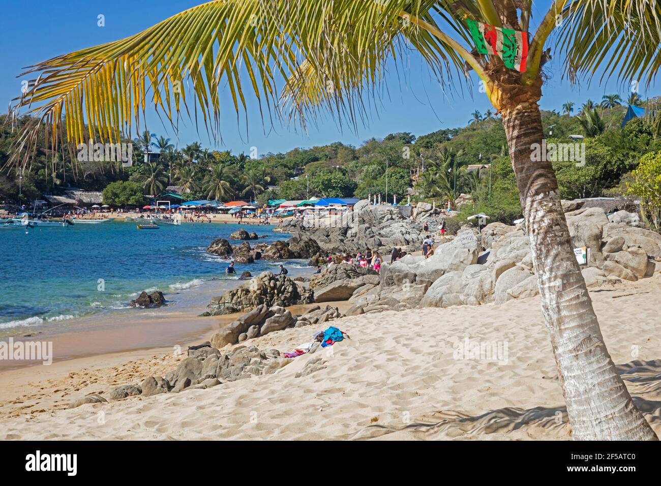 Turisti in una baia riparata con spiaggia di sabbia vicino a Puerto Escondido, San Pedro Mixtepec, Oaxaca, Messico Foto Stock