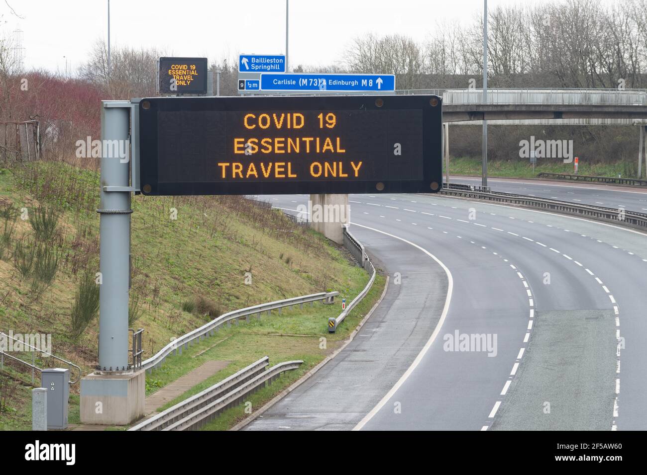 Glasgow, Scotland, UK - 26 marzo 2020: Autostrada M8 molto tranquilla, a volte vuota, con i conducenti ricordati via numerosi 'Covid-19 Essential Travel only' si Foto Stock