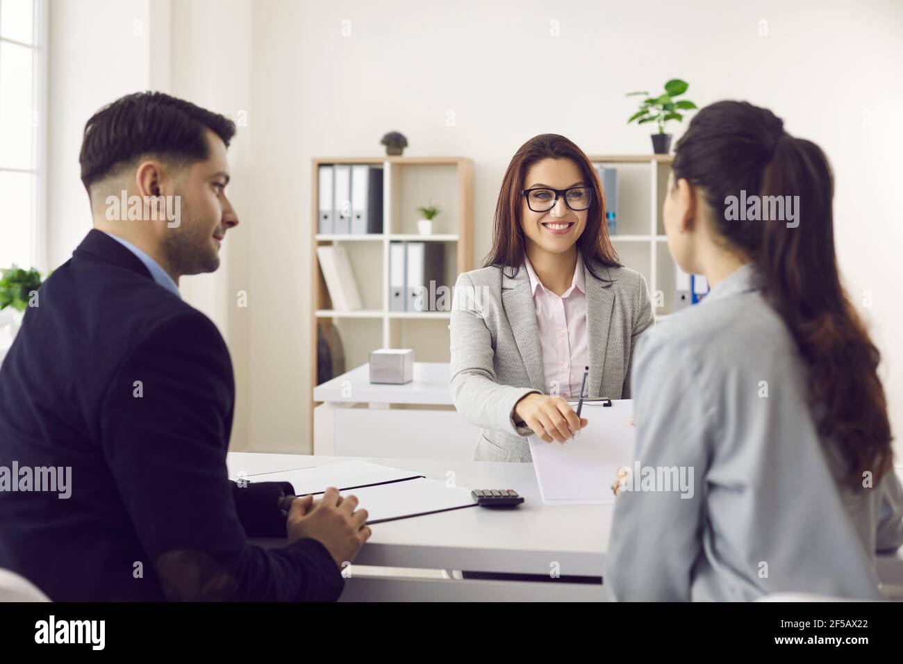 Amichevole lavoratore bancario che dà penna per firmare il contratto promettente bene trattare con il cliente Foto Stock