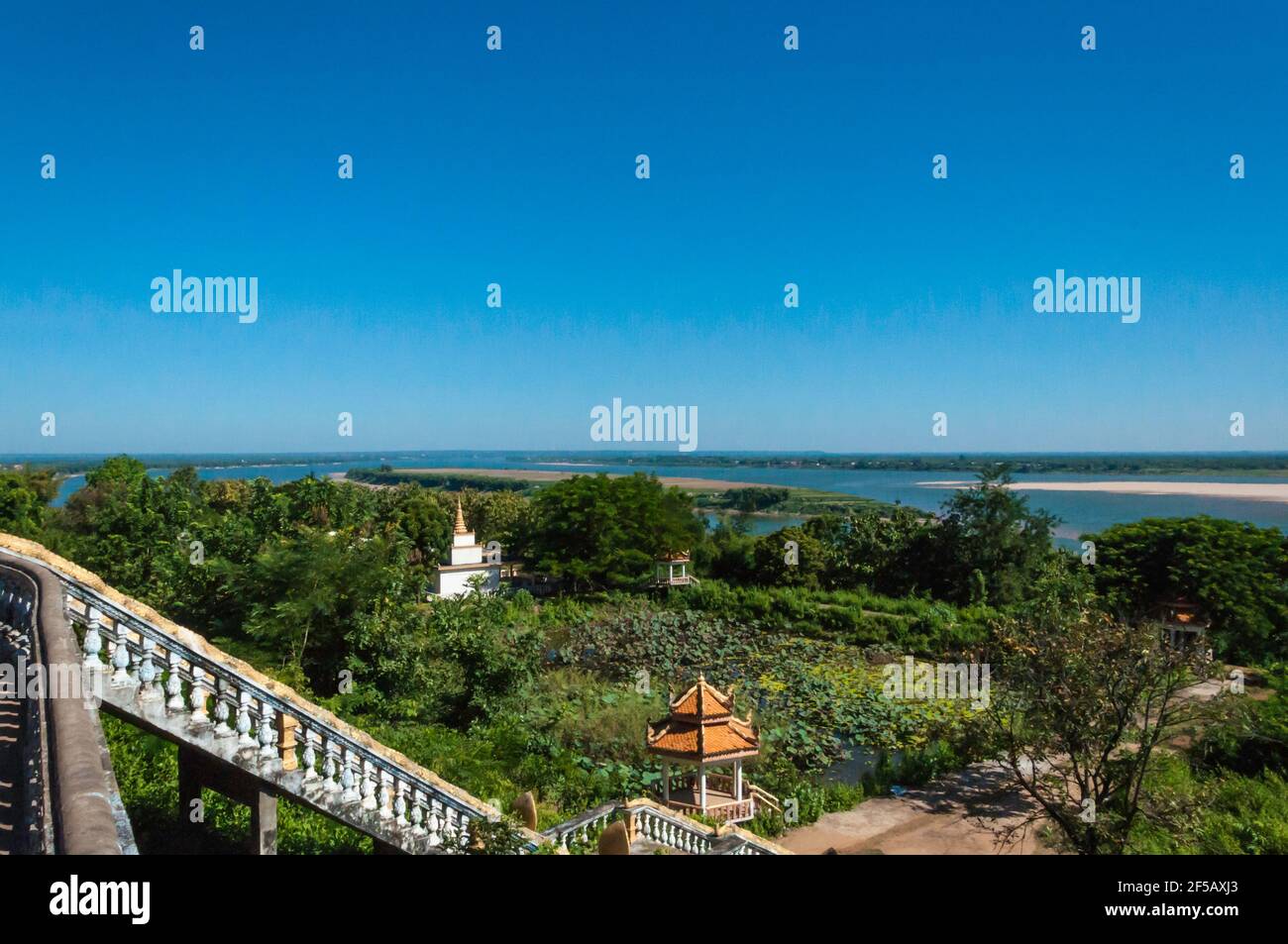 Vista del Mekong da un punto elevato. In primo piano diversi piccoli templi nel paesaggio densamente cresciuto Foto Stock