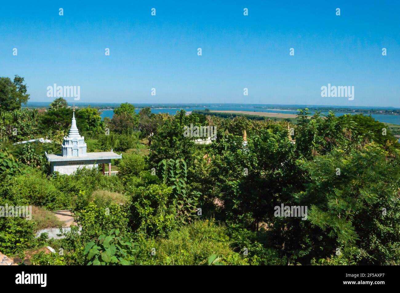 Vista del Mekong da un punto elevato. In primo piano diversi piccoli templi nel paesaggio densamente cresciuto Foto Stock