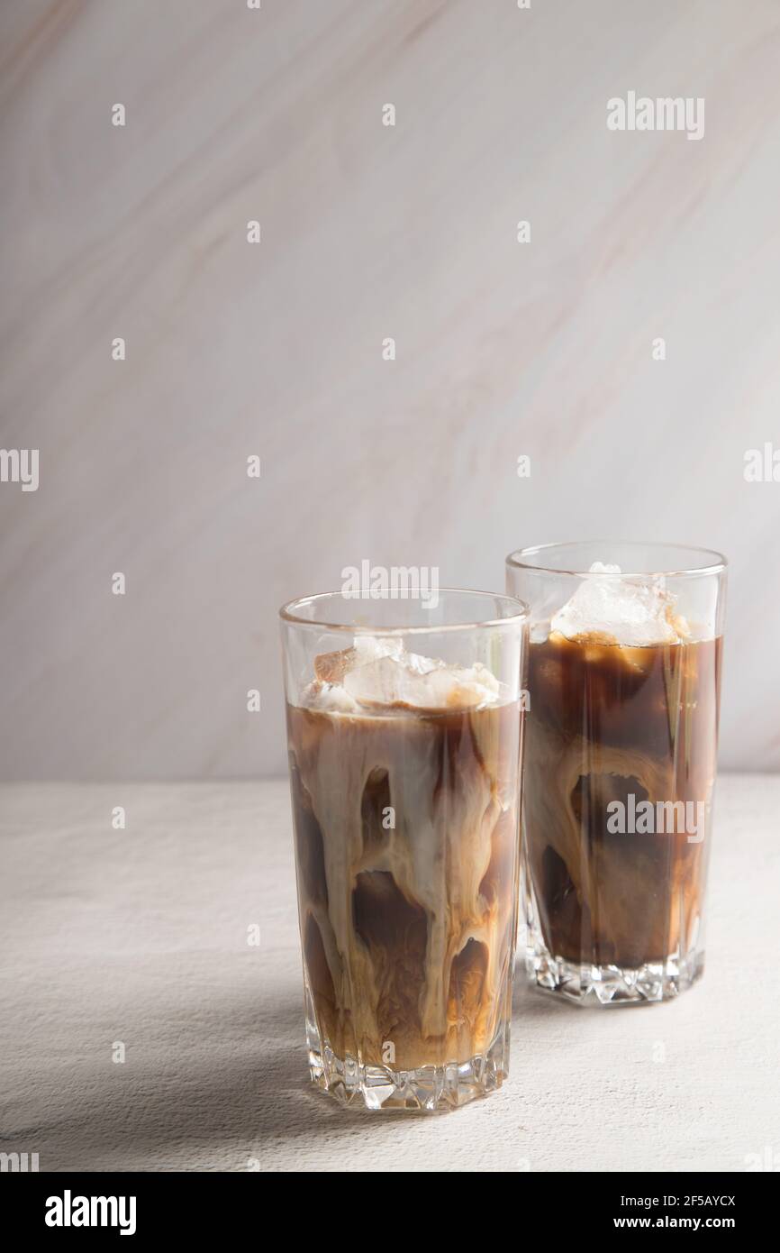 Caffè dolce freddo con latte e ghiaccio su sfondo chiaro. Foto Stock