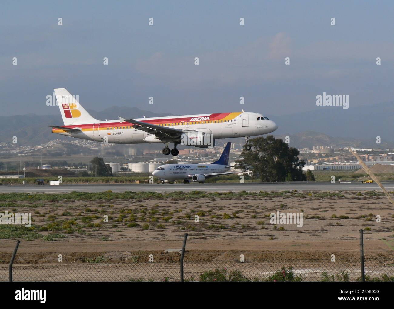 Iberia Airbus A320 atterraggio e Boeing 737 futura in attesa di decollo, aeroporto di Malaga, Spagna. Foto Stock