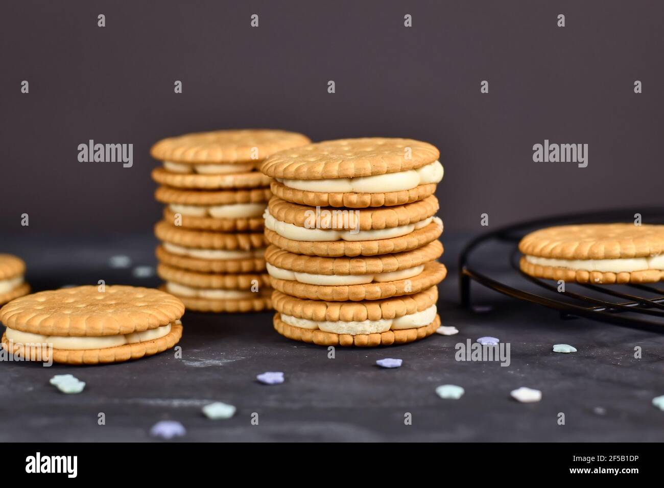Pila di biscotti doppi con panino ripieno di panna su sfondo scuro Foto Stock