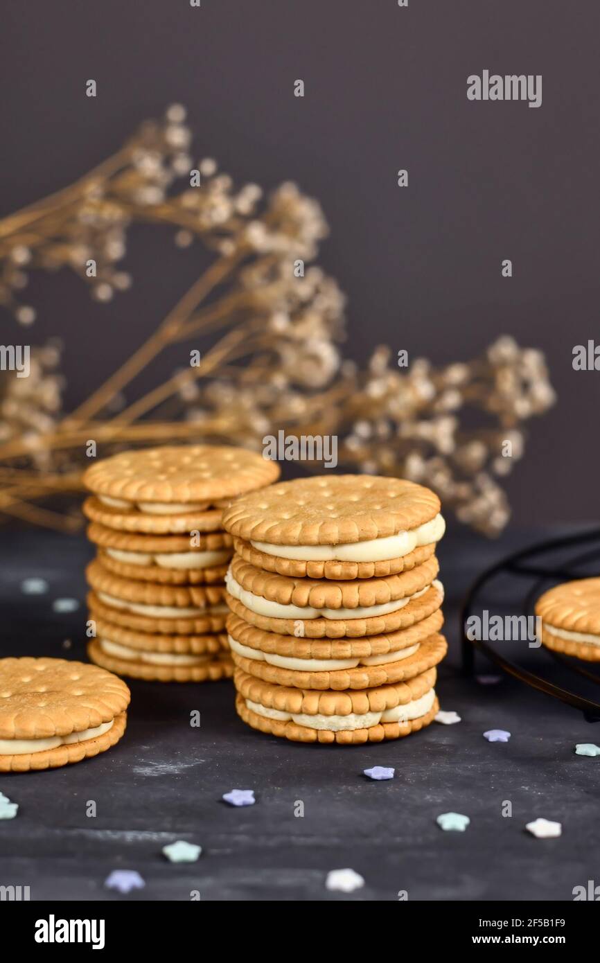 Pila di biscotti doppi con panino ripieno di panna su sfondo scuro Foto Stock