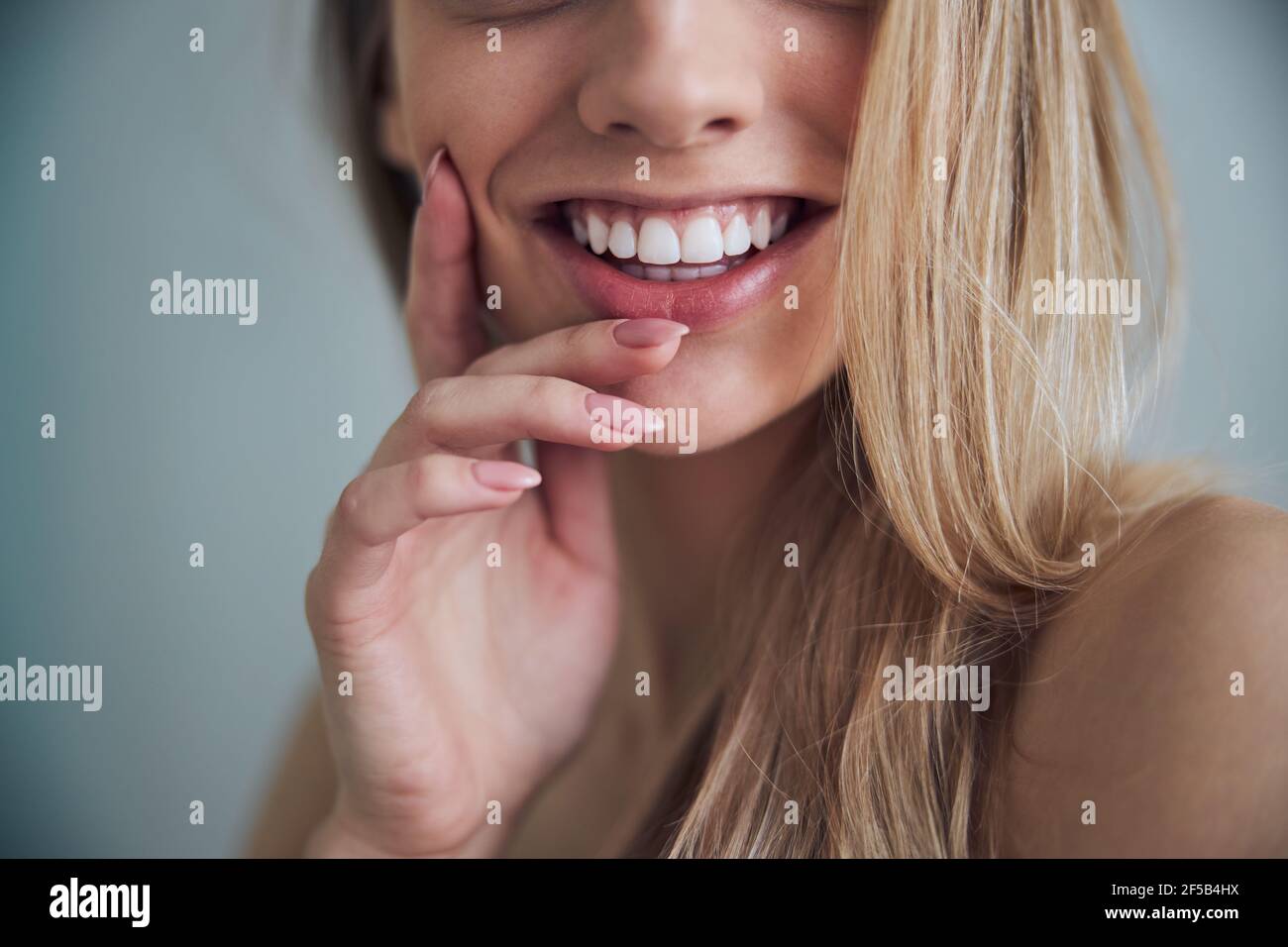 Donna con un sorriso togoteo che tocca la guancia con una mano Foto Stock