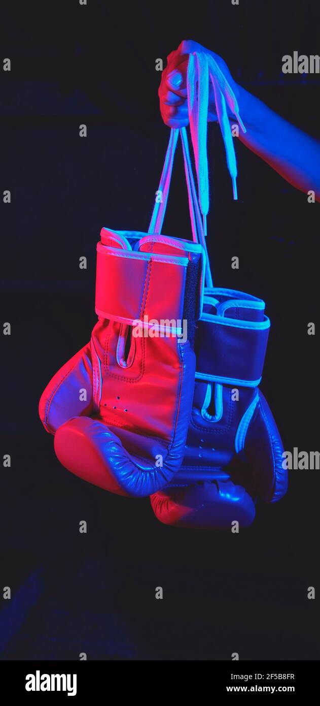 Bella formazione pugile femminile, guanti di pugilato rosso, anello con luci rosse e blu, palestra industriale, luci al neon. Fuoco selettivo Foto Stock