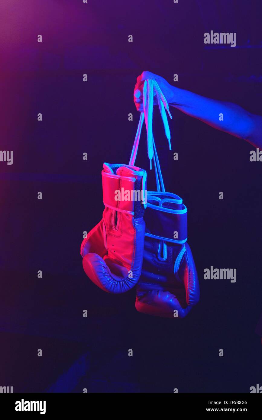 guanti di boxe rossi, anello con luci rosse e blu, palestra industriale, luci al neon. messa a fuoco selettiva Foto Stock