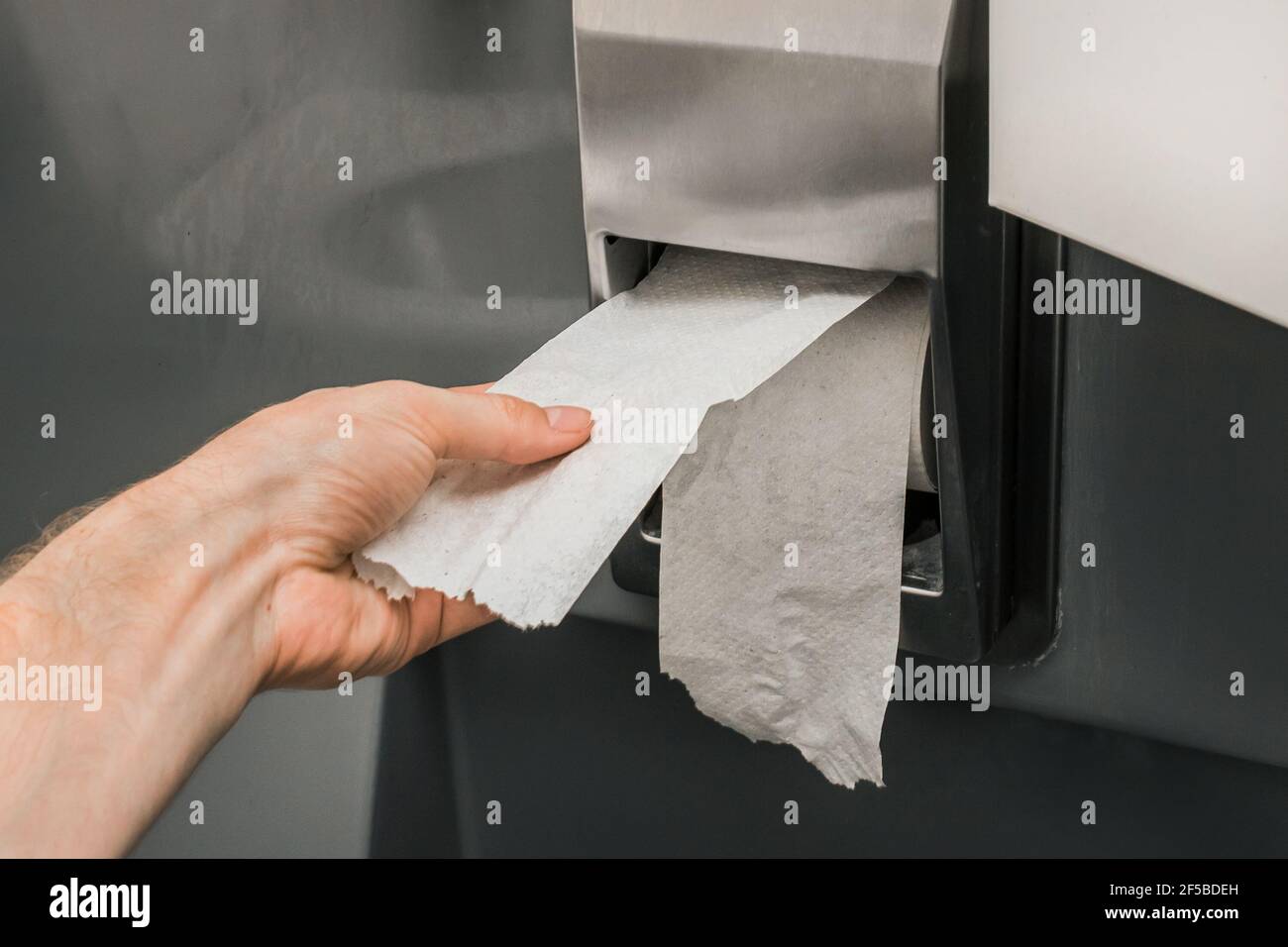La mano dell'uomo toglie o strappa la carta igienica in un rotolo, primo  piano, messa a fuoco morbida Foto stock - Alamy
