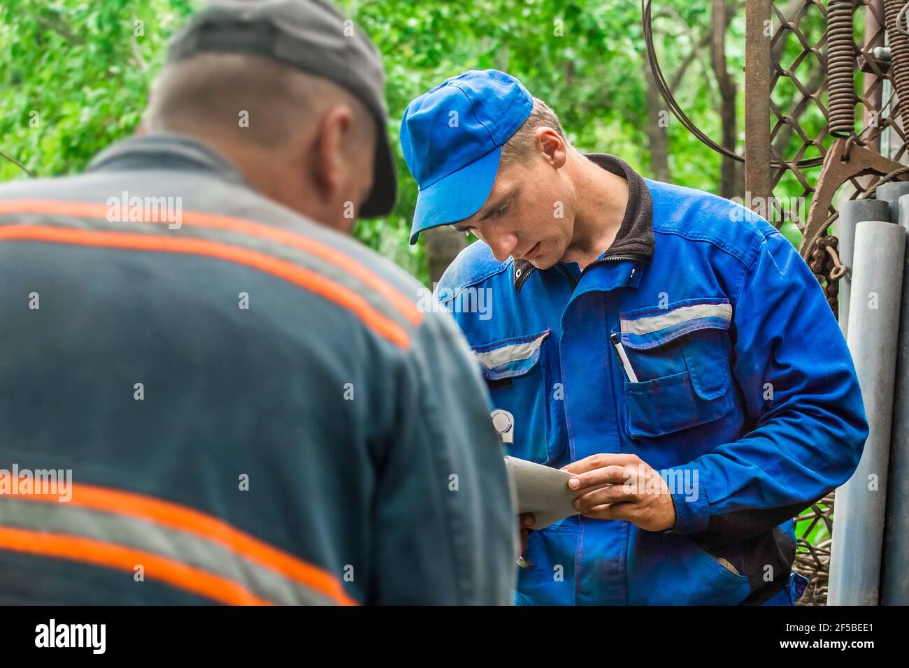 Bielorussia, regione di Minsk - 10 luglio 2020: Due lavoratori europei del gas maschile controllano la riconciliazione dei numeri delle bombole di gas. Foto Stock
